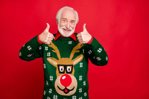 Retrato de positivo alegre funky cinza-cabelo velho homem mostrar polegar-up recomendo inverno tradição temporada descontos desgaste natal x-mas pulôver com antler design patter isolado cor vermelha fundo — Fotografia de Stock