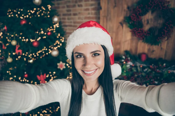 Close up foto de menina alegre positiva desfrutar Natal tempo férias fazer selfie desgaste santa claus headwear em casa com x-mas decoração luzes grinalda dentro de casa — Fotografia de Stock