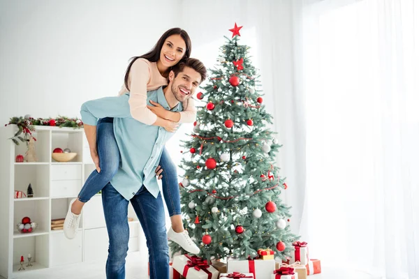 Portret van twee vrolijke mensen romantisch koppel genieten van kerstvakantie x-mas vakantie in huis met groenblijvende decoratieve dennenboom binnen — Stockfoto
