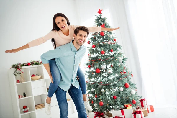 Portret dwóch zabawnych ludzi dziewczyna t podnoszenie rąk niesione przez męża świętować Boże Narodzenie czas x-mas wakacje w domu z dekoracji noel wewnątrz — Zdjęcie stockowe