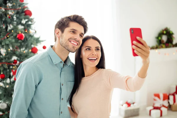 İki kişinin portresi. Cep telefonlarıyla selfie çeken hoş bir adam ve kadın. Evde yeni yıl dekorasyonunun keyfini çıkarın. — Stok fotoğraf
