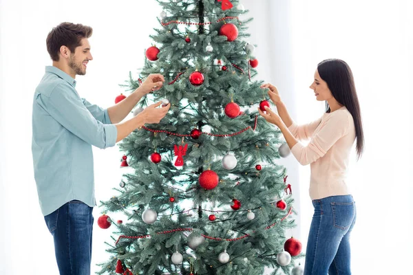 İki güzel eşin portresi. Cam balo tutan köknar ağacı dekore ediyorlar. Evde Noel partisi için Noel tatili hazırlıyorlar. — Stok fotoğraf