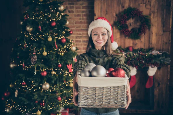 여기 도움 이 필요해. 밝은 갈색 머리의 긍정적 인 소녀의 사진은 많은 바우 블이 들어 있는 상자를 들고 있으며, 실내에 있는 신년 장식 이 가득 한 집에서 크리스마스 축하를 준비하고 있다. — 스톡 사진