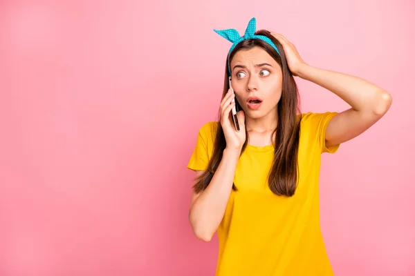 Portret van gefrustreerde hipster met blauwe hoofdband met behulp van moderne technologie in paniek raakt haar hoofd dragen geel t-shirt geïsoleerd over roze achtergrond — Stockfoto
