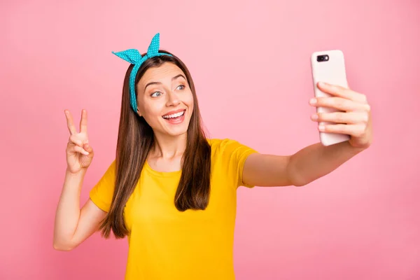 Портрет здивованої дівчини, що робить фото v-знаки усміхнені в жовтій футболці ізольовані на рожевому фоні — стокове фото