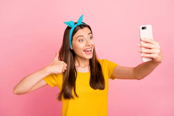 Портрет веселої дівчини, що робить фото з використанням сучасної технології в жовтій футболці ізольований рожевий фон — стокове фото