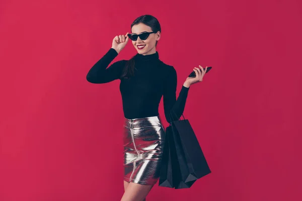 彼女の素敵な外観魅力的なかなり陽気な女性は黒のバッグを運ぶ手のデバイスで保持オンライン新しいものを注文する上で隔離されたmaroonバーガンディマルサラ赤パステルカラーの背景 — ストック写真