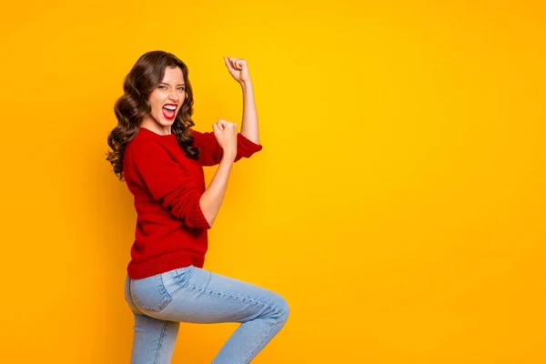 Фото веселой ликующей девушки в джинсах, изолированной на жёлтом ярком фоне, с поднятыми руками, празднующей победу. — стоковое фото