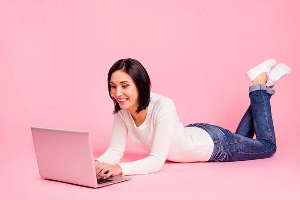 Pleine photo du corps de charmante dame couchée par terre faire des devoirs en utilisant portable porter pull blanc et jeans isolé fond de couleur rose — Photo