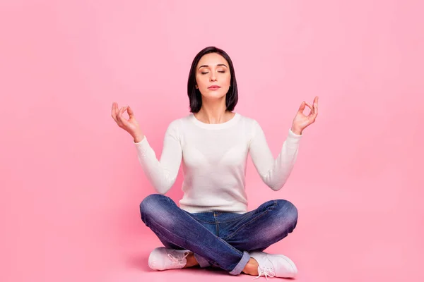 Foto de comprimento total de senhora encantadora sentado no chão relaxado na posição de lótus ioga desgaste pulôver branco e jeans isolado cor rosa fundo — Fotografia de Stock