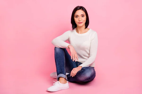 Foto de larga duración de la encantadora dama de negocios sentada en el suelo ropa relajada jersey blanco y pantalones vaqueros aislados de color rosa fondo — Foto de Stock