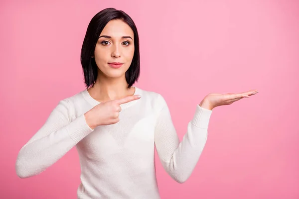 Foto von hübschen Geschäftsfrau zeigt Finger auf offener Handfläche präsentiert neues Produkt tragen weißen Pullover isoliert rosa helle Farbe Hintergrund — Stockfoto