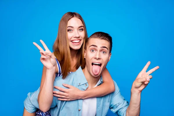 Primer plano retrato de dos simpáticos locos locos tontos alegres alegres alegres personas positivas cerdito-respaldo mostrando v-signo de divertirse engañar aislado en brillante brillo vivo vibrante fondo de color azul —  Fotos de Stock