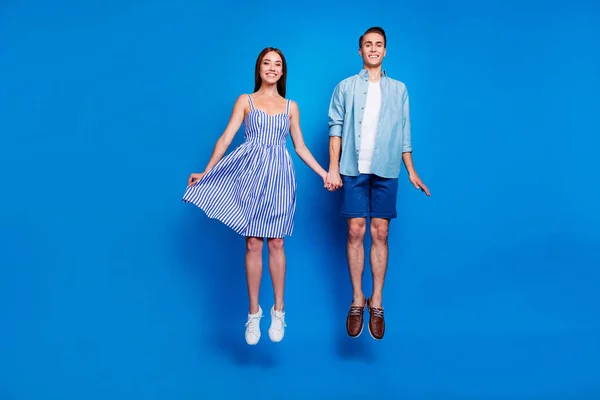 Full length body size view of her she she his he two nice attractive funky dreamy cheerful glad partners holding hands jumping up isolated over bright vivid shine vibrant blue color background — стоковое фото