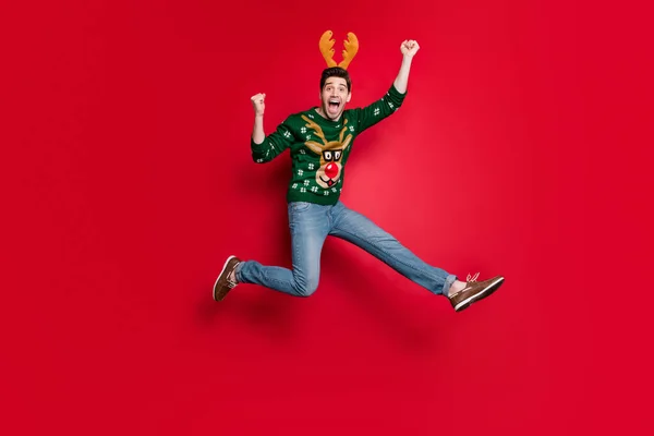 Foto in voller Größe von lustigen Kerl springen hoch läuft zu Weihnachten kostenlos einkaufen wild schreiend tragen Pullover mit hässlichen Hirsch Ornament isoliert rote Farbe Hintergrund — Stockfoto