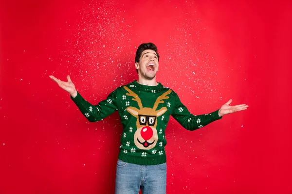 Retrato dele ele agradável atraente bonito alegre alegre sonhador cara vestindo camisola de veado verde desfrutando de lazer jogando neve isolada sobre brilhante brilho vívido cor vermelha vibrante fundo — Fotografia de Stock