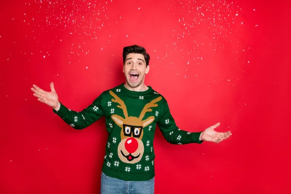 Portrait of his he nice attractive handsome cheerful cheery glad guy wearing green deer sweater having fun throwing snow isolated over bright vivid shine vibrant red color background — Stock Photo, Image
