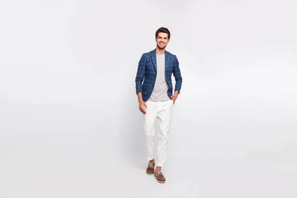 Полноразмерная фотография очаровательного мужчины, идущего в движении, одетого в современные блейзерные брюки пиджака, изолированные на белом фоне — стоковое фото