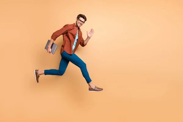 Full length body size view of he nice attractive cheery chappy content guy jumping in air carrying laptop running fast late-up meeting απομονωμένο πάνω από μπεζ χρώμα παστέλ φόντο — Φωτογραφία Αρχείου