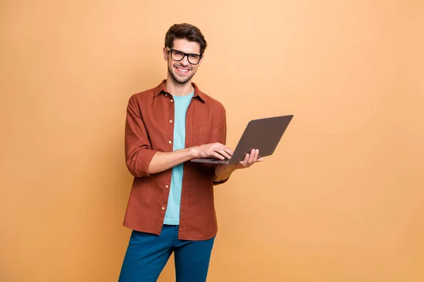 Portrait of his he nice attractive cheerful cheery successful content smart clever brunet guy agent broker holding in hands laptop working isolated over beige color pastel background — ストック写真