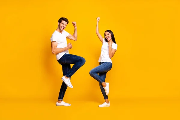 Foto de corpo inteiro de senhora par e cara fãs apoiando time de futebol favorito levantando punhos usar roupa casual isolado cor amarela fundo — Fotografia de Stock