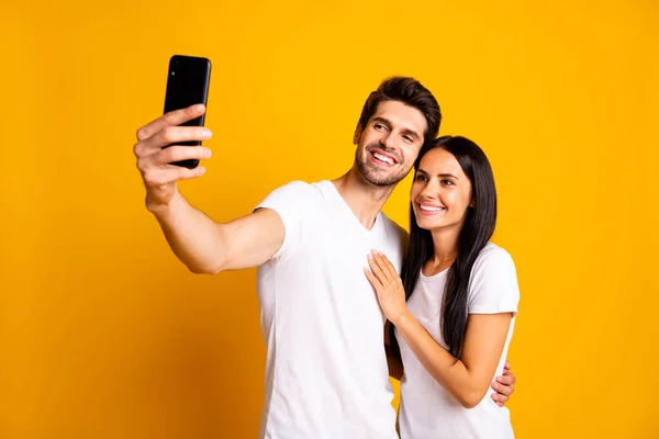 Foto di due persone che tengono il telefono in mano scattando selfie per il nuovo post indossare abiti casual isolato colore giallo sfondo — Foto Stock