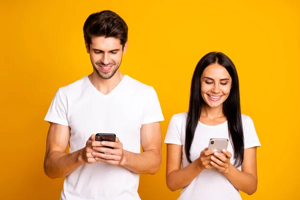 Foto de dos personas no se preocupan el uno al otro mira los teléfonos comprobando instagram seguidores usan ropa casual aislado color amarillo fondo —  Fotos de Stock