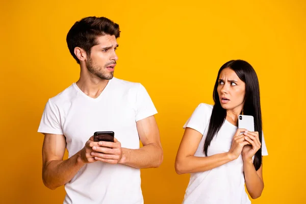 Foto von zwei Personen mit Telefonen, die einander nicht vertrauen private Informationen tragen lässige Kleidung isoliert gelbe Farbe Hintergrund — Stockfoto