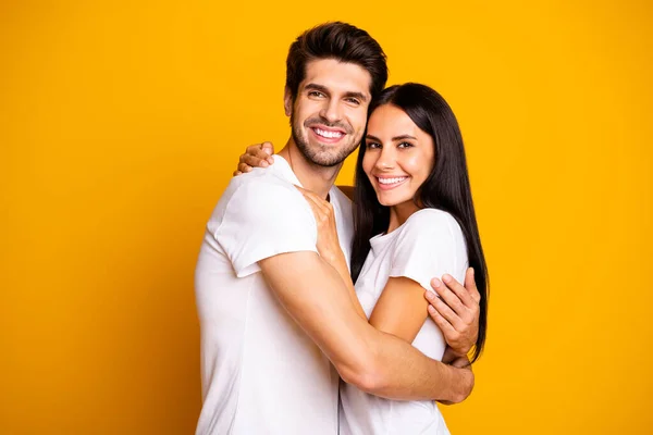 Foto av fantastiska par i kärlek hålla varandra i händerna havent sett för åldrar bära casual vita t-shirts isolerad gul färg bakgrund — Stockfoto