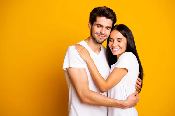 Foto av fantastiska par i kärlek hålla varandra i händerna nära ögon bära casual vita t-shirts isolerad gul färg bakgrund — Stockfoto