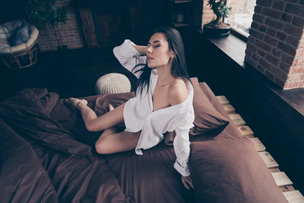 Portré róla ő szép kinézetű gyönyörű vonzó szeretnivaló álmodozó lány ül az ágyon ugratja Önt az ipari tégla fa padláson modern belső stílus lakás hotel beltéri — Stock Fotó