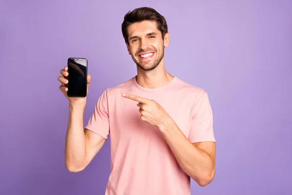 Portrait of his he nice attractive cheerful cheery glad confident guy wearing pink tshirt holding in hands pointing at digital device isolated on violet purple lilac pastel color background — ストック写真