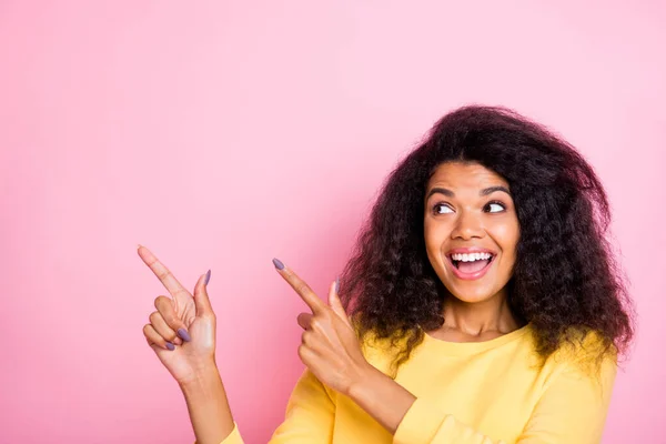 Close up photo of funny funky amazed black girl see wonderful advertisements point index finger show wow omg suggest select follow way wear yellow lifestyle pullover isolated over pink color — ストック写真