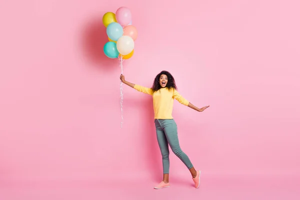 Foto em tamanho completo de encantadora menina africana espantada segurar muitos balões voando no ar presente dado para aniversário sentir desgaste alegre roupa elegante elegante isolado sobre fundo cor pastel — Fotografia de Stock