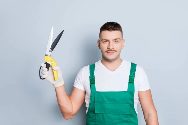 Foto de chico fuerte guapo sosteniendo tijeras de jardinería brazo escuchar orden del cliente sobre el recorte de arbustos usan mazmorras verdes fondo gris aislado — Foto de Stock