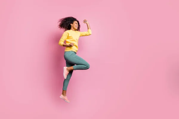 Full size photo of excited cheerful optimistic delightful rejoicing ecstatic crazy glad good hipster enjoying her fortune jumping up raising fists up wear yellow sweater pants isolated background