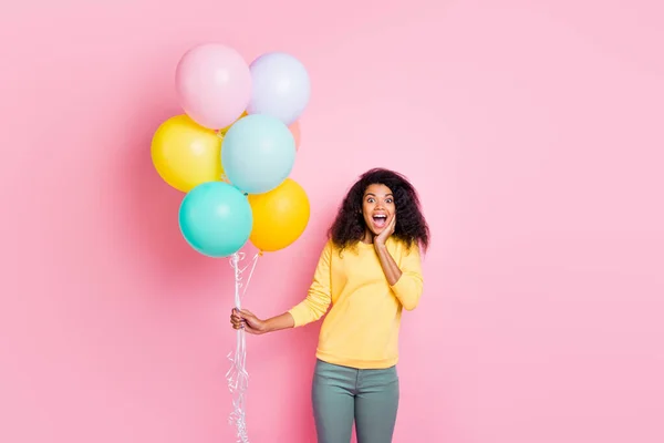Portret van opgewonden geschokt meisje houden veel ballonnen krijgen cadeau voor verjaardag 8-maart onder de indruk schreeuw wow omg dragen gele trui broek geïsoleerd over pastel kleur achtergrond — Stockfoto