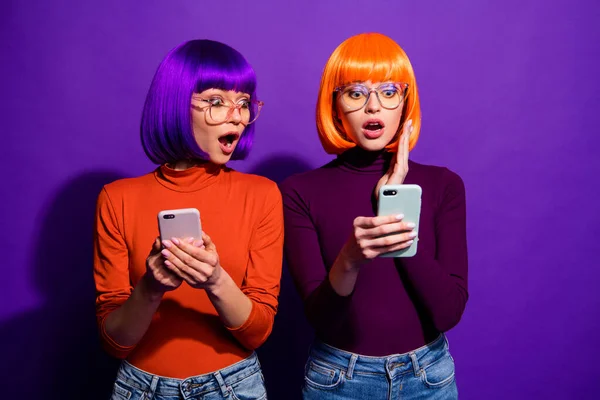 Портрет двух красивых привлекательных милые веселые веселые удивленные девушки в париках с помощью клеток чтения новостей, глядя СМИ изолированы над ярким ярким ярким фиолетовым фиолетовым фиолетовым цветом фона — стоковое фото