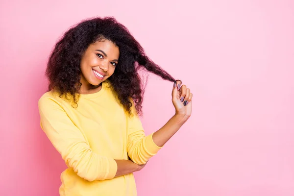 Portrét okouzlující pozitivní africká dívka dotknout její vlasy těšit nové anti lupy lupy kondicionér, aby její účes pohled lesk nosit trendy žlutý jumper izolované přes růžové barevné pozadí — Stock fotografie