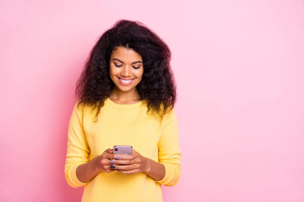 Portrait of positive cheerful black lady feel interested use her cell phone read feednews in social network account wear good looking trend outfit isolated over pastel pink color background — ストック写真