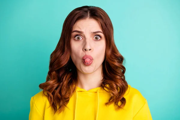 Photo scared afraid curly wavy frightened youngster sticking tongue out with teasing face expression close up isolated over turquoise vivid color background