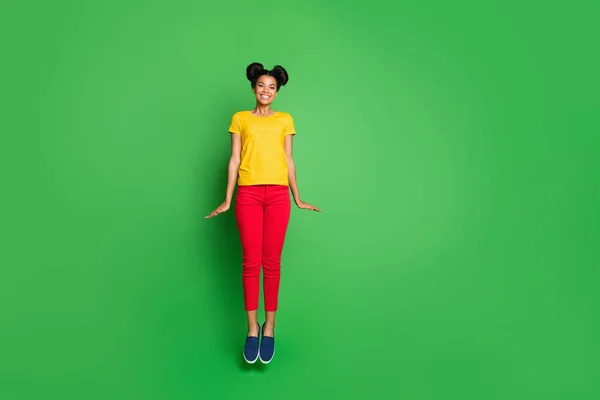 Πλήρης φωτογραφία του σώματος του αρκετά σκούρο δέρμα κυρία άλμα υψηλή τρελή καλοκαιρινή διάθεση φορούν casual κίτρινο t-shirt κόκκινο παντελόνι απομονωμένο πράσινο φόντο — Φωτογραφία Αρχείου