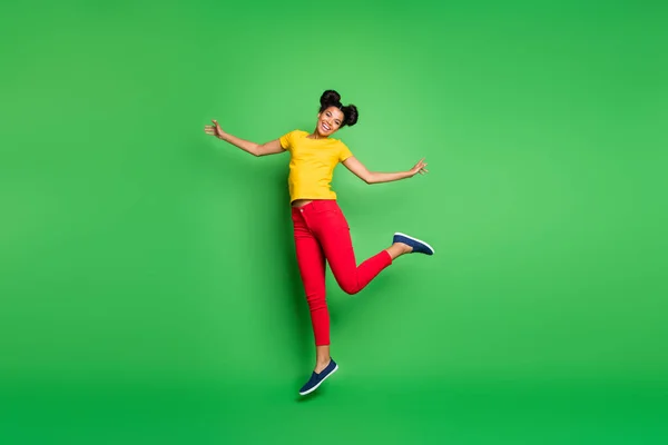 全长照片，漂亮的深色皮肤女士在比赛中跳高支援队身穿休闲黄T恤红色裤子孤立的绿色背景 — 图库照片
