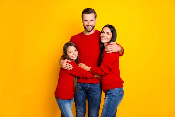 Фото веселого милого симпатичного сімейства в джинсах джинсових червоних светрів, що обіймають один одного в любові ізольовані на жовтому яскравому кольоровому фоні — стокове фото