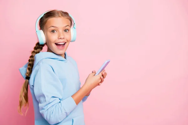 Zdjęcie dość mało pani trzyma telefon słuchać popularny fajny utwór w nauszniki nosić casual niebieski bluza pullover odizolowany pastelowy różowy kolor tło — Zdjęcie stockowe