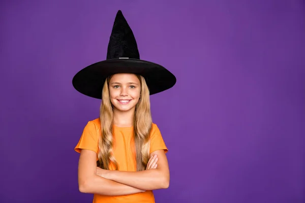 Foto de pequena bruxa senhora com braços cruzados jogando paranormal criatura halloween festa desgaste laranja t-shirt chapéu de assistente isolado roxo cor fundo — Fotografia de Stock