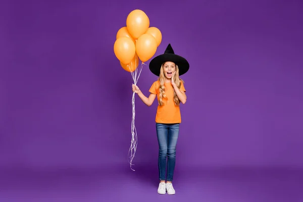 Full size foto di eccitata piccola signora festa di Halloween con palloncini d'aria è venuto a bambini partito a tema indossare arancione t-shirt cappello strega isolato colore viola sfondo — Foto Stock