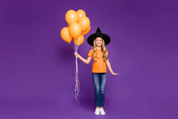 Foto em tamanho completo da pequena bruxa senhora festa de Halloween segurando muitos balões de ar veio para as crianças festa tema desgaste laranja t-shirt chapéu de assistente isolado cor roxa fundo — Fotografia de Stock