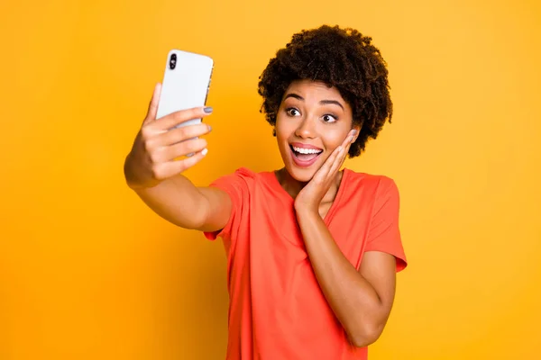 Photo de joyeux mignon charmant belle belle jolie petite amie noire peau prenant selfie avec son téléphone tenu dans ses mains portant t-shirt isolé sur fond jaune couleur vive — Photo