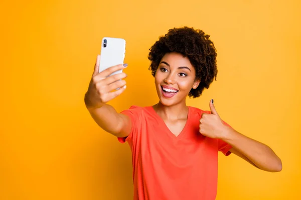 Foto de modelo ondulado rizado alegre de moda elegante hermosa novia encantadora pulgar encima del símbolo sonriendo dentívamente aprobando algo usar camiseta aislado amarillo brillante color de fondo — Foto de Stock